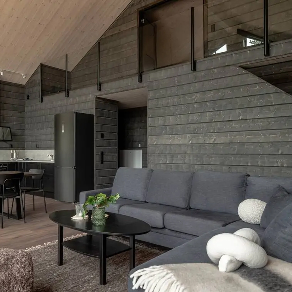 Loft i fjällhus med glasräcke och trappa i trä.