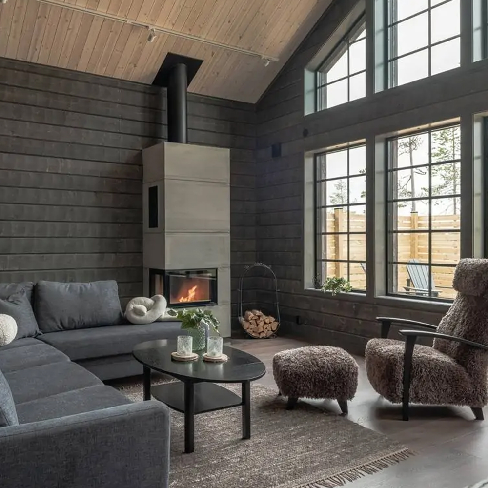 Interiörbild av fjällhus med kamin i vardagsrum.